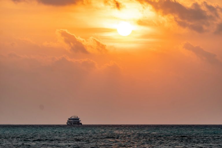 silhouette of ship on sea during sunset